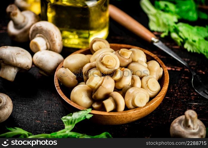 Fragrant pickled mushrooms in a plate with greens. On a black background. High quality photo. Fragrant pickled mushrooms in a plate with greens.