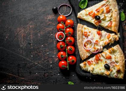 Fragrant slices of pizza on a cutting Board. On dark rustic background. Fragrant slices of pizza on a cutting Board.