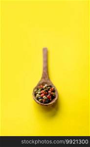 Fragrant spices in a spoon closeup, isolated on yellow background. Organic vegetarian food, grocery assortment, natural eco products, healthy lifestyle concept. Spices in a spoon closeup, yellow background