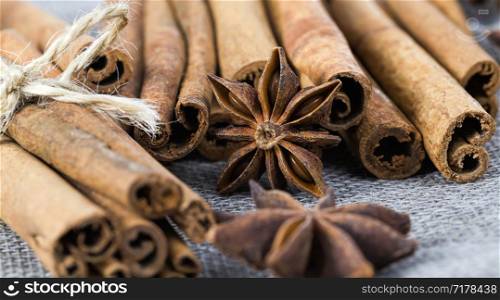 fragrant sticks of bark cinnamon on the tablecloth along with dry and fragrant star anise, close-up of delicious Oriental spices in the territory of the kitchen. fragrant sticks of bark cinnamon
