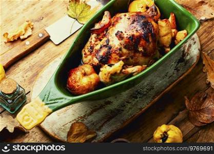 Fragrant tasty partridge roasted with quince on rural wooden surface. Delicious homemade chicken with quince