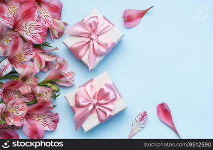 Frame for the text of congratulations with  flowers of Alstroemeria and gift boxes on a blue background. Greeting card with natural colors. Background for text with alstromeria. Flat lay, top view.