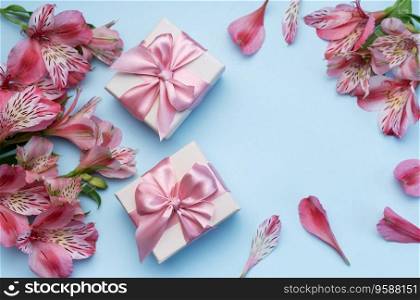 Frame for the text of congratulations with  flowers of Alstroemeria and gift boxes on a blue background. Greeting card with natural colors. Background for text with alstromeria. Flat lay, top view.