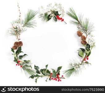 Frame from pine tree branches with ilex leaves on white background. Christmas floral flat lay