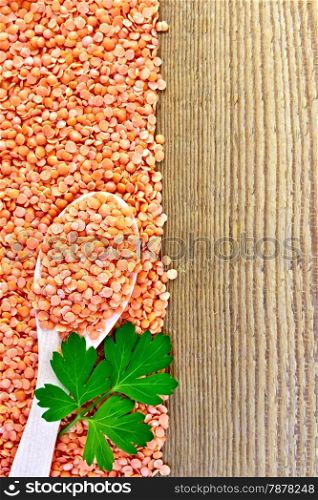 Frame from red lentils with a spoon and parsley leaves on a wooden board
