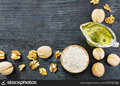 Frame from walnut flour in a bowl, oil in sauceboat and nuts on a black wooden board background from above