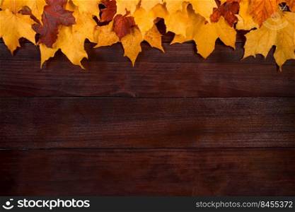 Frame from yellow autumn leaves on a brown wooden background. Fallen foliage. Backdrop for design. Copy space.. Frame from yellow autumn leaves on a brown wooden background. Fallen foliage. Backdrop for design.