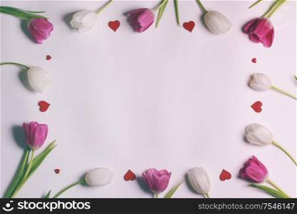 Frame made of colourful tulips and red hearts Valentines day background. Frame made of colourful tulips