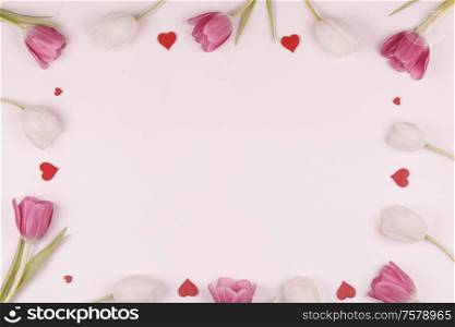 Frame made of colourful tulips and red hearts Valentines day background. Frame made of colourful tulips