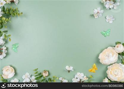 frame made of fruit tree flowers and green leaves on a green background. Summer and springtime composition with copyspace. Flat lay. Summer and springtime background
