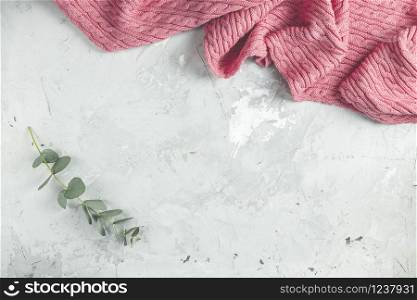 Frame made of pink blanket and eucalyptus leaves on gray concrete background. Spring concept. Flat lay, top view, copy space