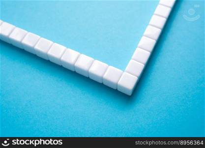 Frame made of white blocks on a blue background. Abstraction, object structure. Place for text, copy space. Turn 90 degrees