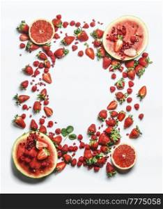 Frame made with red fruits and berries  watermelon, grapefruit, strawberries, raspberries and pomegranate seeds. Healthy refreshing summer food. Top view wit copy space.