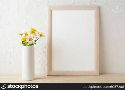 Frame mockup with white and yellow chamomiles in vase. Poster white frame mockup. Empty white frame mockup for presentation design.. Frame mockup with white and yellow chamomiles in vase