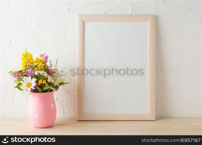 Frame mockup with wild flowers in pink vase. Portrait or poster white frame mockup. Empty white frame mockup for presentation artwork.. Frame mockup with wild flowers in pink vase