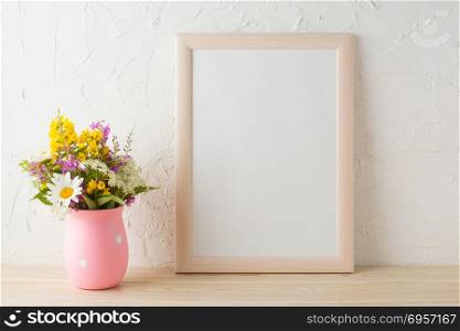 Frame mockup with wild flowers in pink vase. Portrait or poster white frame mockup. Empty white frame mockup for presentation artwork.. Frame mockup with wild flowers in pink vase