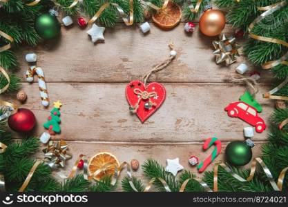 frame of Fir tree branches with Christmas decoration on wooden background, flat lay. gift, present heart. Fir tree branches with Christmas decoration on wooden background, flat lay. Space for text