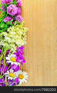 Frame of flowers of clover, chamomile, fireweed and meadowsweet on the background of a wooden board