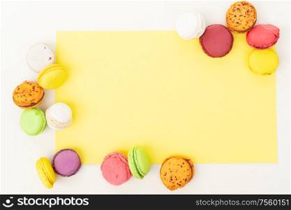 Frame of fresh fresh macaroon biscuit, top view over yellow background. Fresh macaroon confection