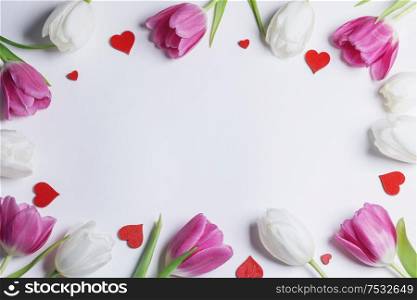 Frame of fresh tulip flowers and decorative hearts isolated on white background. Frame of tulips and hearts