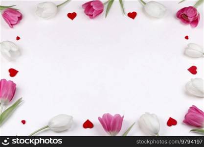 Frame of fresh tulip flowers and decorative hearts on white background with copy space. Frame of tulips and hearts