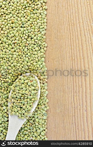 Frame of green lentils with a spoon on the left side of wooden boards