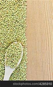Frame of green lentils with a spoon on the left side of wooden boards