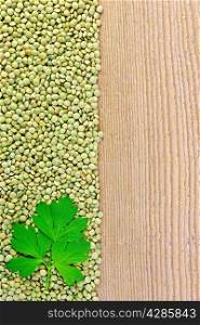 Frame of green lentils with parsley leaf on the left side of wooden boards