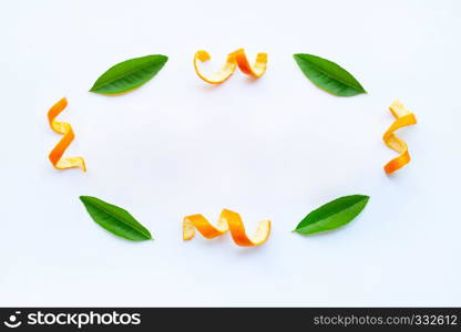 Frame of orange peels with green leaves on white background.