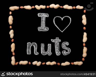 "Frame of peanuts on a black background and chalk inscription "I love nuts""