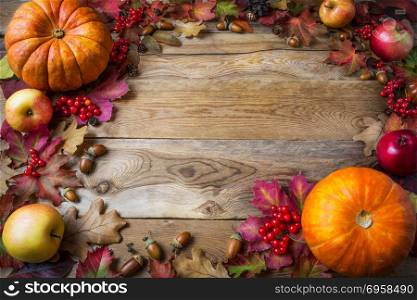Frame of pumpkins, apples, acorns, berries and fall leaves on wooden background. Thanksgiving background with seasonal vegetables and fruits. . Frame of pumpkins, apples, acorns, berries and fall leaves on wo