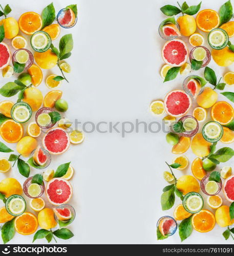 Frame of various colorful citrus fruits: lemon, lime, orange and grapefruit with green leaves and glasses of refreshing lemonade drinks on white background, top view. Healthy lifestyle. Layout.