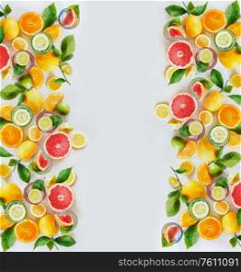 Frame of various colorful citrus fruits: lemon, lime, orange and grapefruit with green leaves and glasses of refreshing lemonade drinks on white background, top view. Healthy lifestyle. Layout.