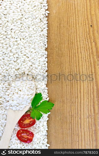 Frame of white rice with a spoon, tomato and parsley on a wooden board
