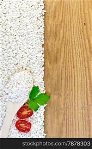 Frame of white rice with a spoon, tomato and parsley on a wooden board