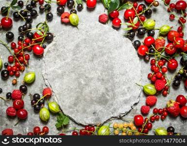 Frame of wild berries with free place for text. On the stone table.. Frame of wild berries with free place for text.
