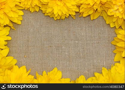 Frame of yellow flowers against a background of rough cloth
