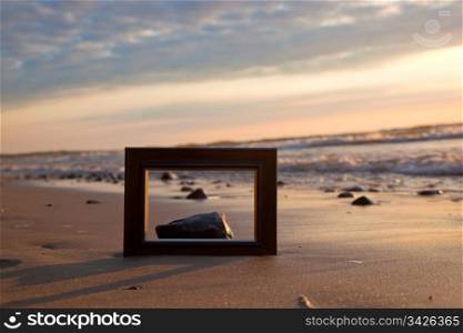 Frame on the beach at sunset. Conceptual, memories from holidays.