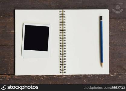 Frame photo and brown book on wood table background.