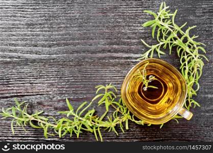 Frame with rosemary herbal tea in a glass cup on wooden board background from above
