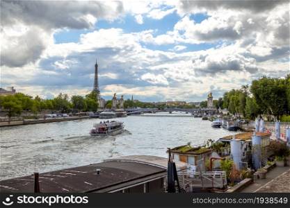 France, Paris. Summer day. River Seine with a view of the Eiffel Tower. Many houses on the water moored at granite embankments. Houses on the Water off the Banks of the Seine