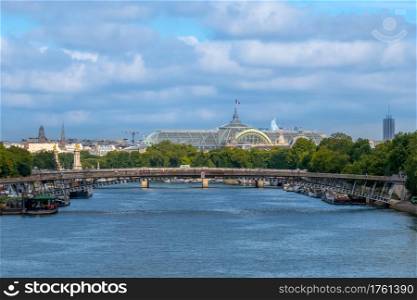 France. Summer day in Paris. Cloudy sky over the Seine. Glass roof of the Grand Palace. Bridges over the Seine and Grand Palace