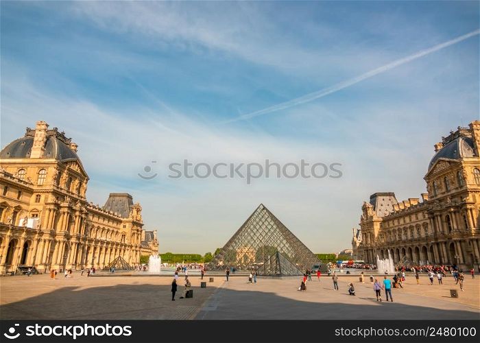 France. Summer sunny day in Paris. Courtyard of the Louvre Museum with fountains and blue sky. Glass pyramid and tourists. Courtyard of the Louvre Museum on a Sunny Summer Day