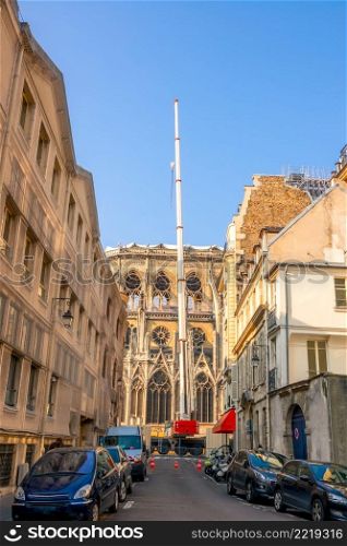 France. Summer sunny day in Paris. Narrow street with parked cars. Crane restores Notre Dame after after a fire. Crane in a Narrow Street on the Restoration of Notre Dame