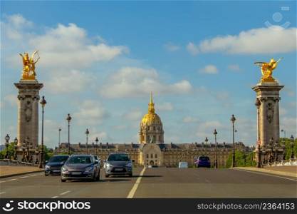 France. Sunny summer day in Paris. Cars on the bridge of Alexander III and facade of the Esplanade Invalides. Traffic on the Bridge in Front of the Esplanade Invalides