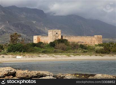 Frangocastello Castle on the south coast of Crete, with the great bulk of the Lefki Ora (White Mountains) rising behind it, under a stormy sky. April 2009