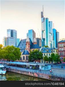 Frankfurt afterglow cityscape with modern archtecture, business district skyscrapers, restaurants, tour boat at Main river, Germany