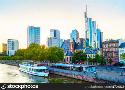 Frankfurt afterglow cityscape with modern archtecture, business district skyscrapers, restaurants, tour boat at Main river, Germany
