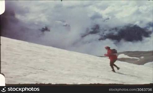 Frau lauft einen verschneiten Gletscher hinauf.