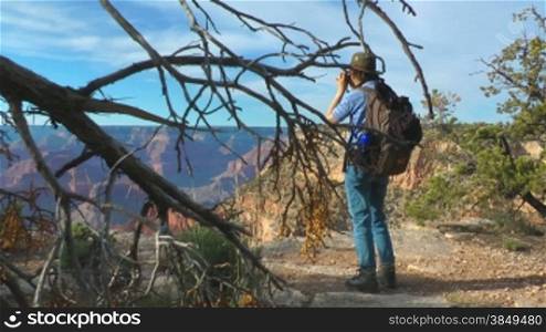 Frau steht auf einer Erh?hung mit Fernglas am Grand Canyon